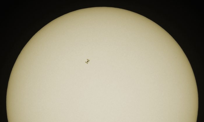 Ein Einzelbild mit der Silhouette der ISS vor der Sonnenscheibe.